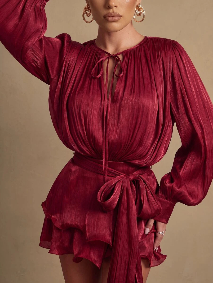 Close-up of the burgundy pleated dress bodice, tie-front neckline, bishop sleeve, and waist sash