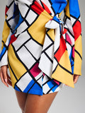 Close-up of side tie waist and straight mini hem on colorful geometric wrap dress