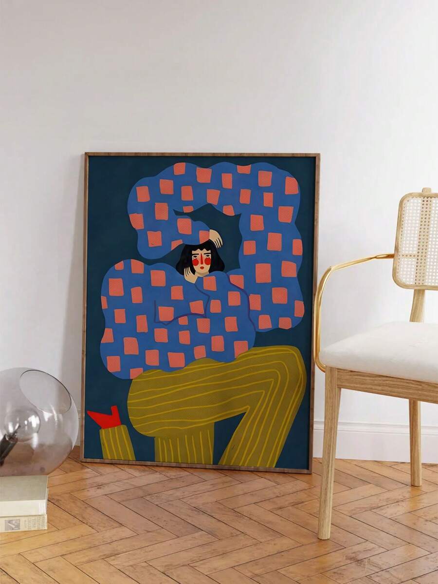 Abstract seated human figure canvas art in wood frame beside a woven chair