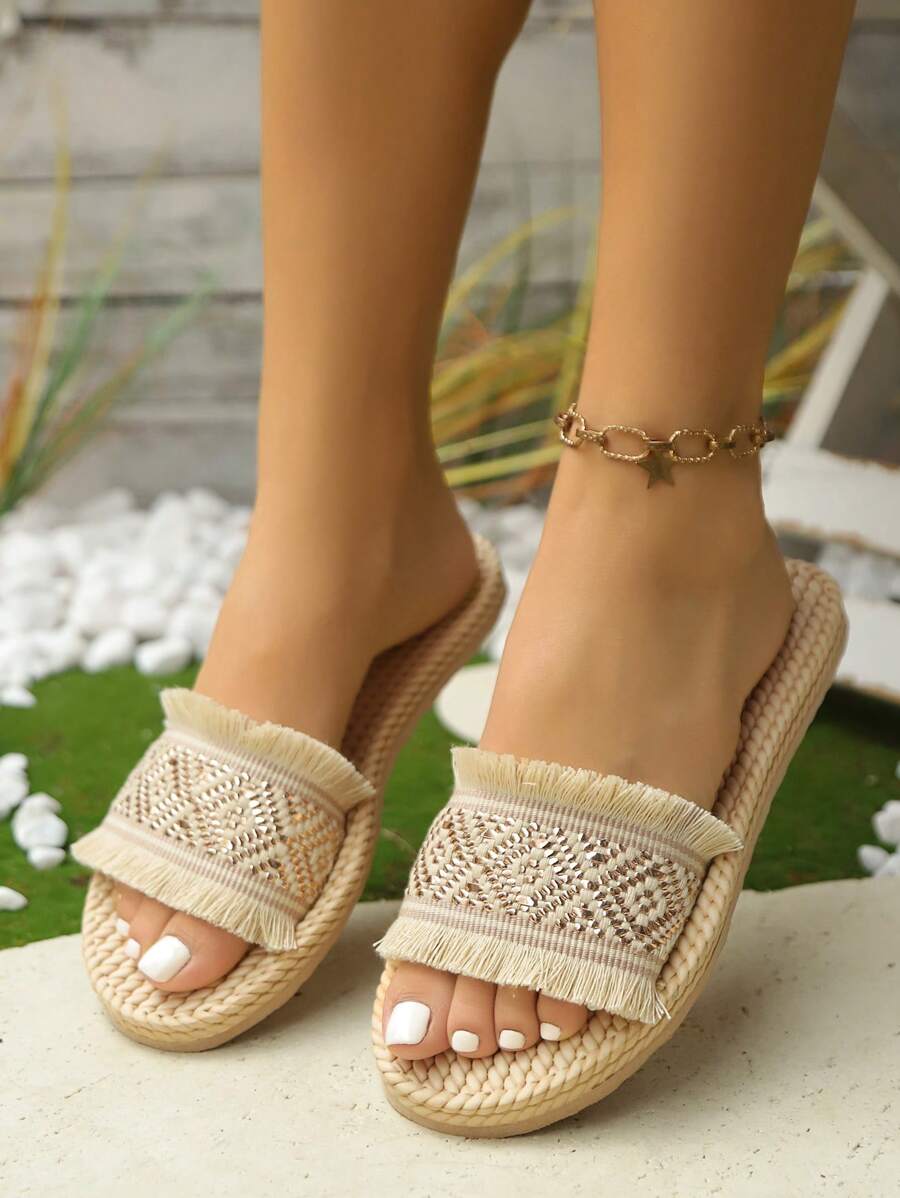 High-angle on-foot view of beige fringed geometric platform slide sandals outdoors