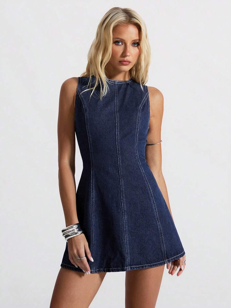 Front studio view of dark indigo sleeveless denim mini dress with sculpted seams and A-line skirt