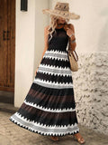 Front view of black and white graphic print halter maxi dress with tiered skirt
