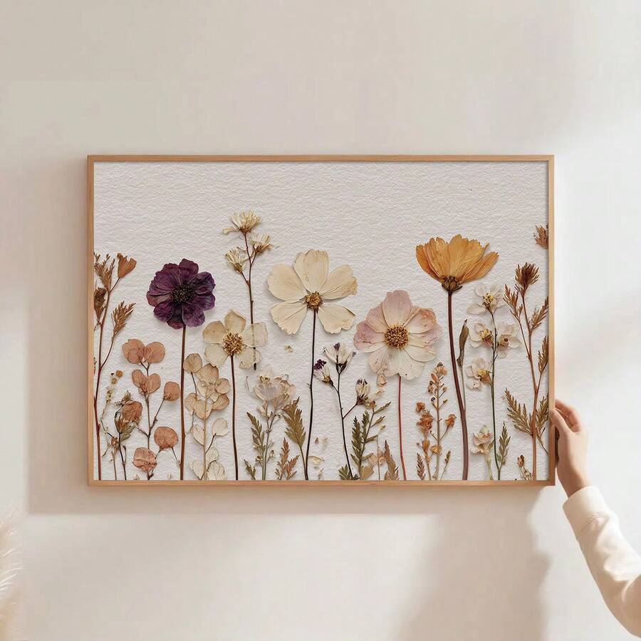 Hand-held view of vintage dried wildflower canvas art in a light wood display frame