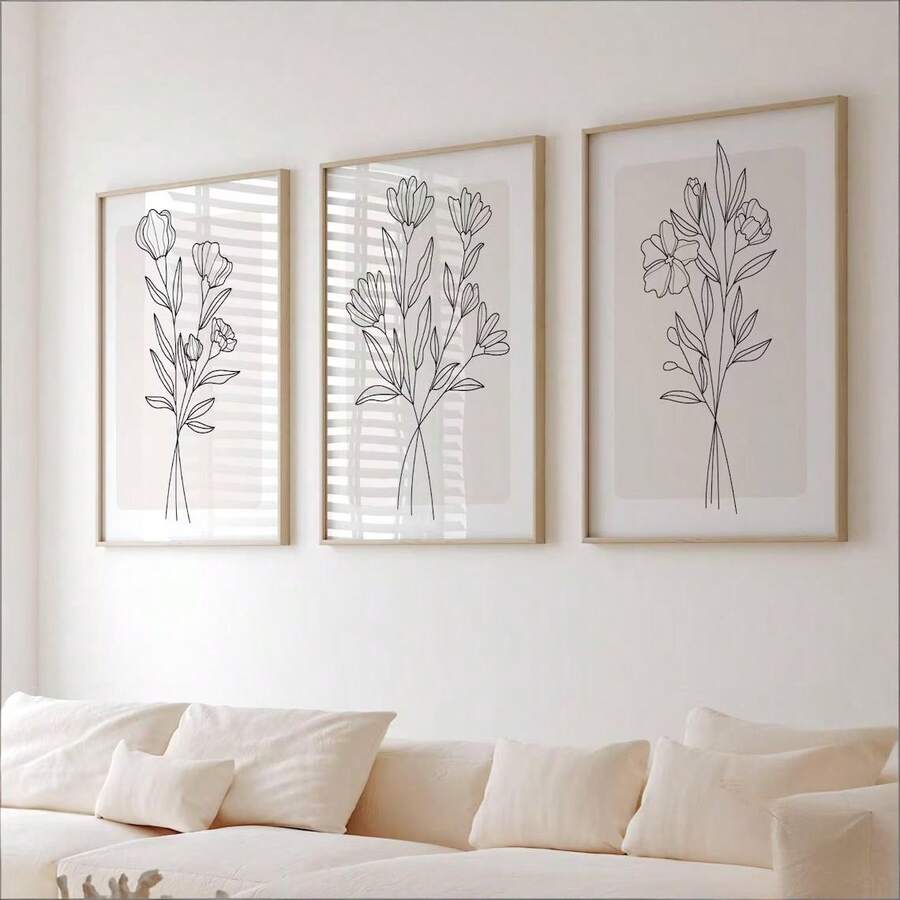 Close living room view of three minimalist botanical prints in light wood frames