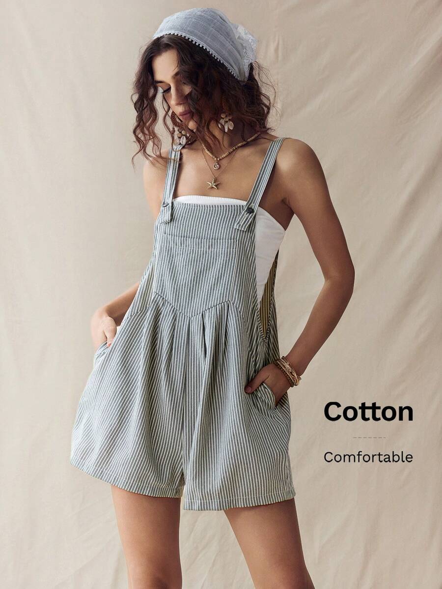 Front three-quarter view of light gray pinstriped overall romper with hands in side pockets