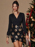 A woman models a black long-sleeve mini dress with gold sequined floral patterns, standing next to a decorated Christmas tree.