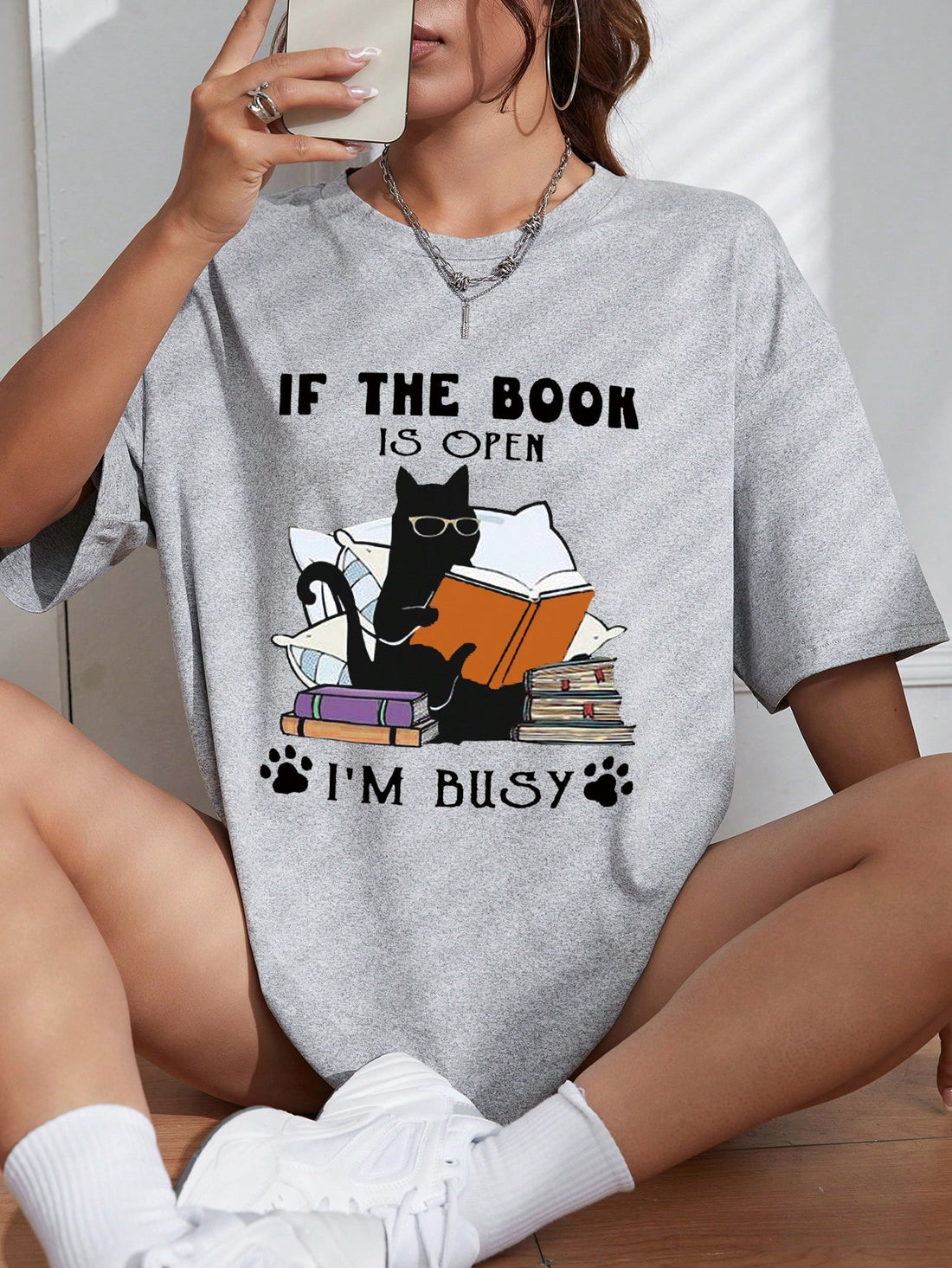 Stay focused on your reading with our Busy Bookworm Cartoon Graphic Tee. Featuring the playful phrase "If The Book Is Open, I'm Busy," this fun and trendy shirt is perfect for book lovers. Made with soft, high-quality materials, it offers both comfort and style for your busy reading days.