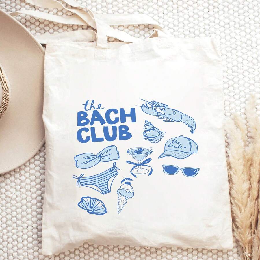 Flat lay front view of white canvas tote bag with blue The Bach Club bridal graphic