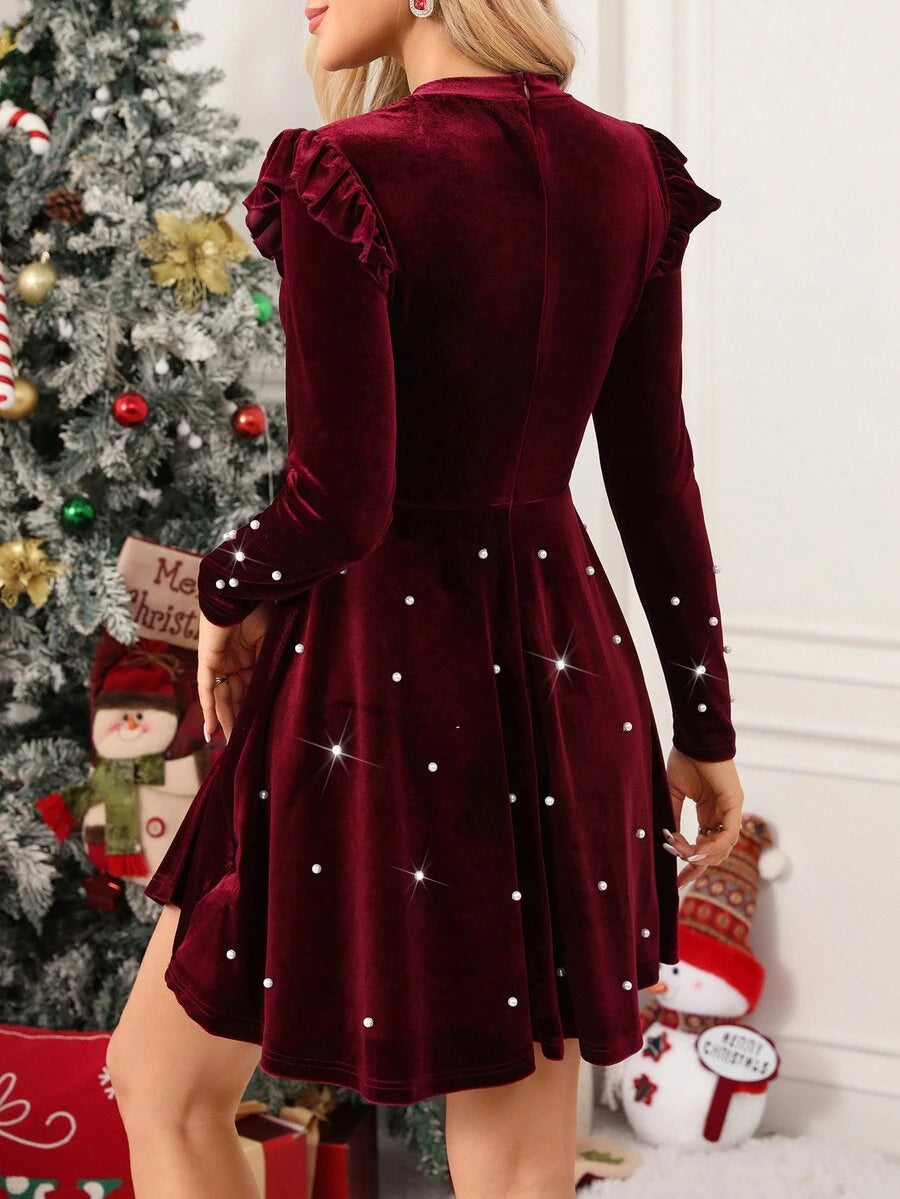 Back view of burgundy long-sleeve velvet dress with pearl-studded flared skirt