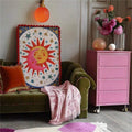 Unframed celestial sun and moon canvas print with red pom-pom trim in an eclectic lounge