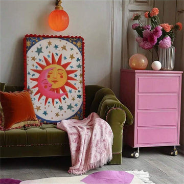 Unframed celestial sun and moon canvas print with red pom-pom trim in an eclectic lounge
