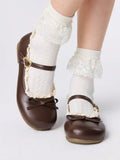 Front three-quarter view of brown bow Mary Jane flats worn with white lace socks