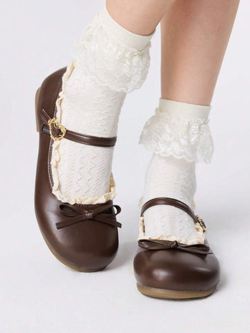 Front three-quarter view of brown bow Mary Jane flats worn with white lace socks