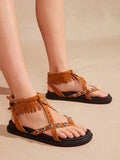 Chestnut boho fringe ankle-strap flat sandals worn with open-toe cross straps