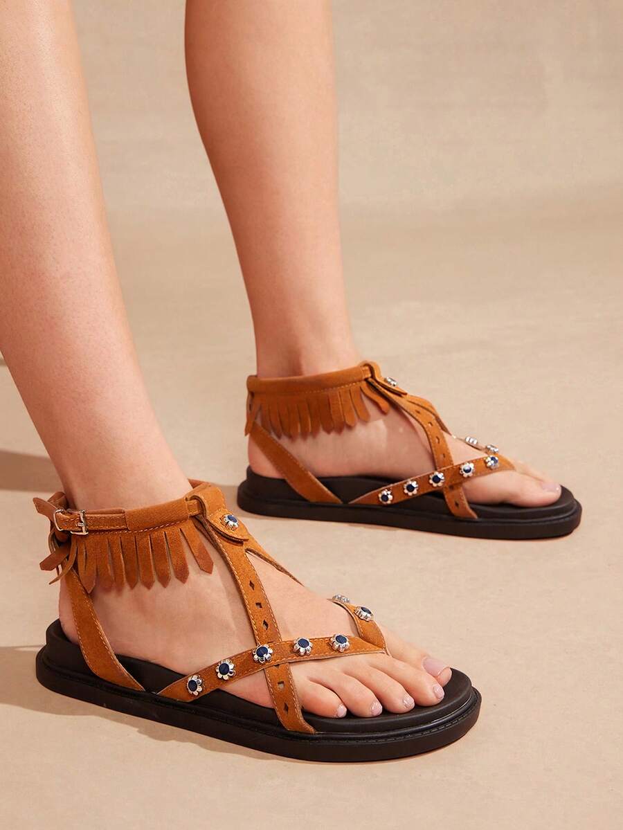 Chestnut boho fringe ankle-strap flat sandals worn with open-toe cross straps