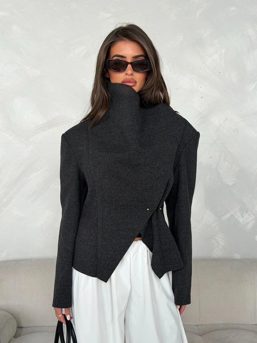 Front view of dark charcoal short jacket with high collar, diagonal wrap panel and small gold-tone fasteners
