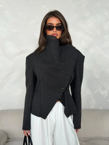 Front view of dark charcoal short jacket with high collar, diagonal wrap panel and small gold-tone fasteners