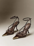 Front three-quarter view of glossy chocolate-brown pointed-toe strappy stiletto sandals with ankle buckles