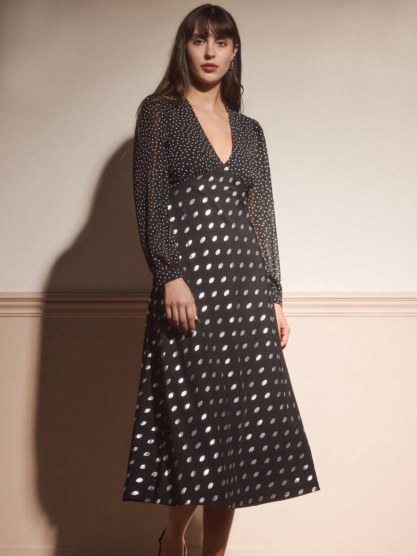 Elevate your autumn wardrobe with this stunning black midi dress that's equal parts sophisticated and fun. The vintage-inspired V-neckline and long sleeves offer timeless elegance, while shimmering metallic polka dots add a playful sparkle that catches the light beautifully. Perfect for dinner dates, cocktail parties, or any occasion calling for effortless chic style. The midi length provides a flattering silhouette that works for any body type, making this dress a versatile go-to piece for the cooler month