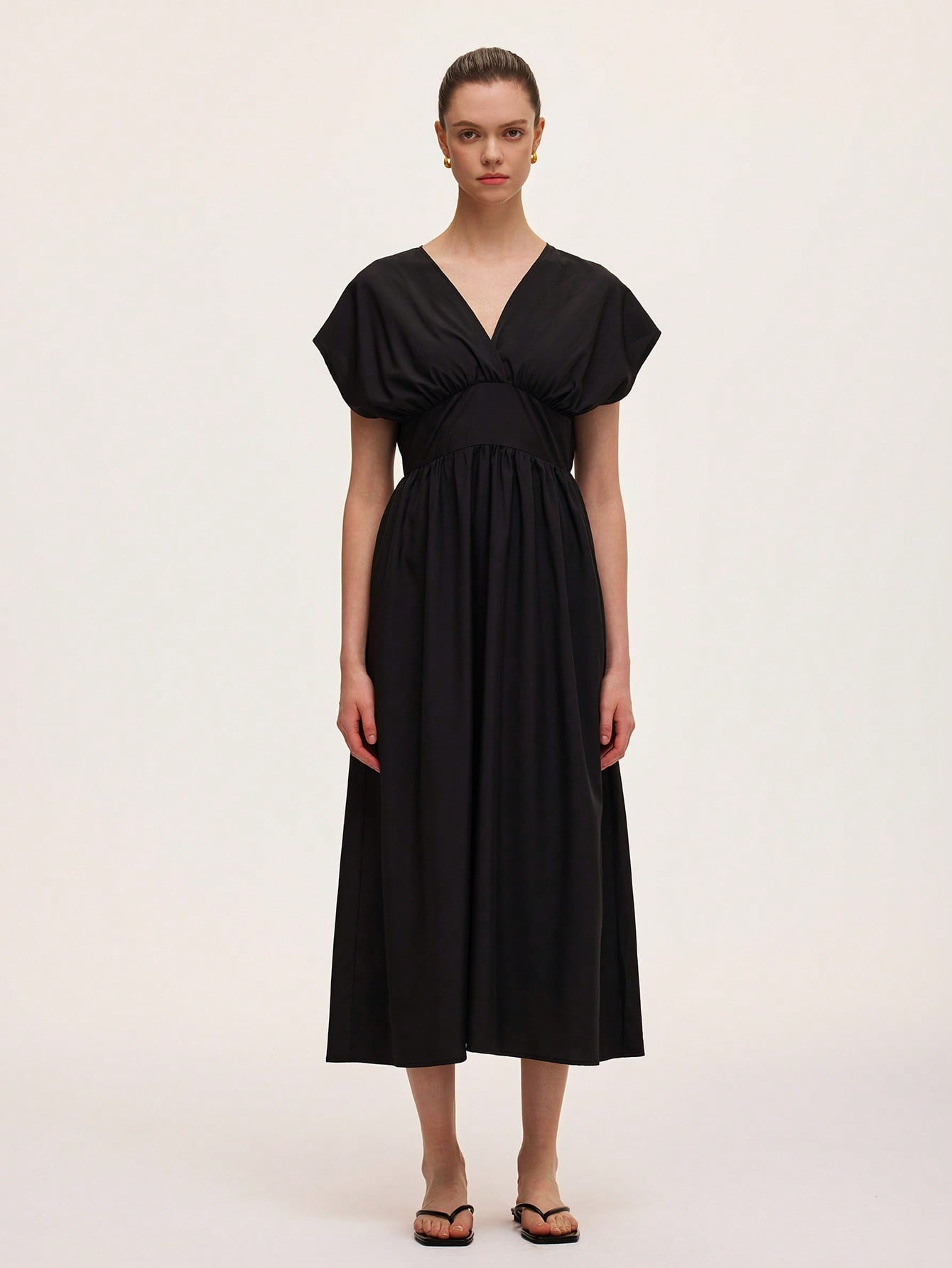 Step out in style with this chic black V-neck dress featuring a flattering draped design and a cinched waist that effortlessly highlights your silhouette. Perfect for any occasion, it combines comfort and elegance with a playful twist, making you feel confident and ready to turn heads wherever you go.