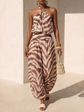 Front courtyard view of brown striped halter jumpsuit with twisted neckline and harem legs