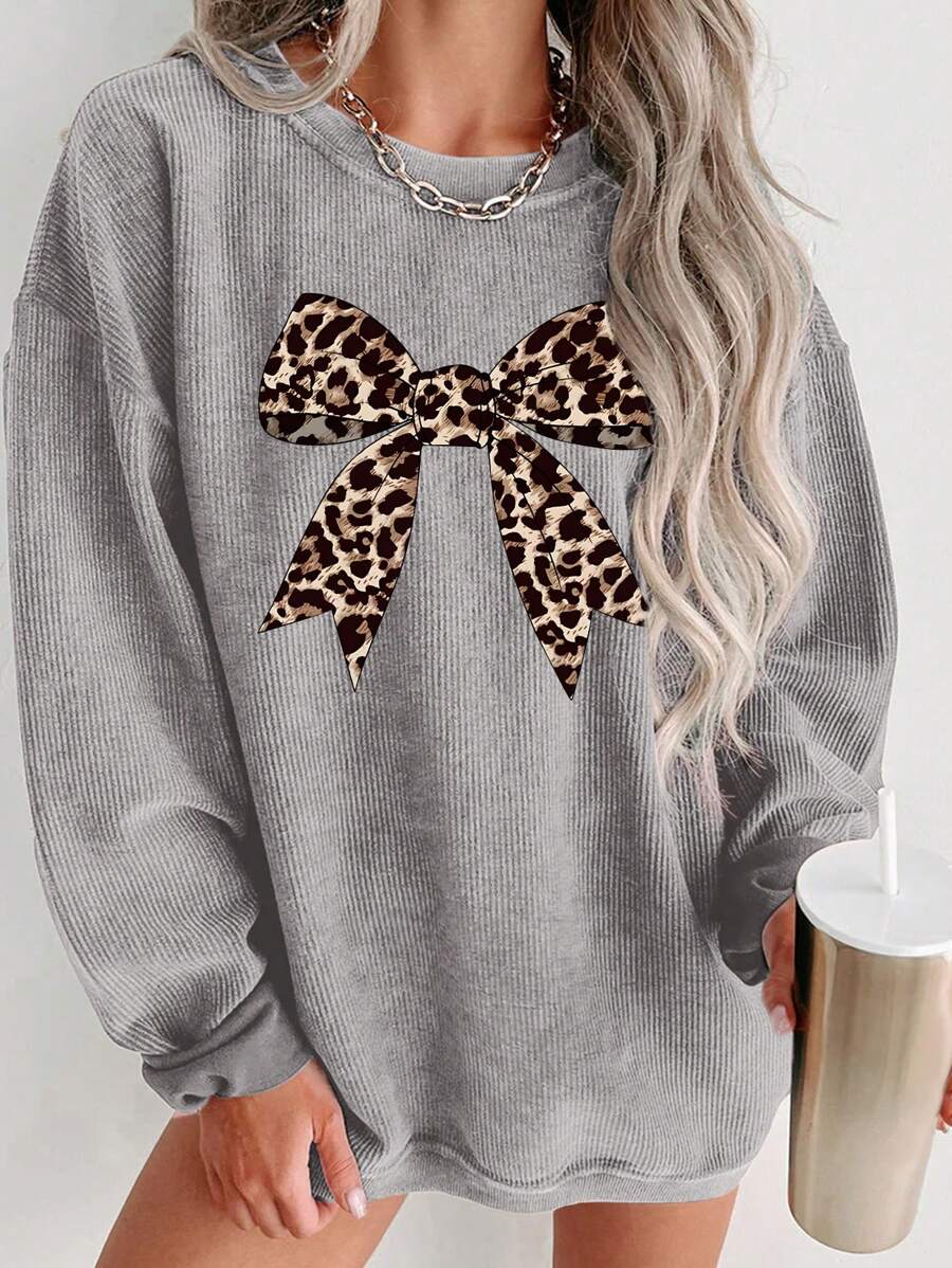 Front worn view of grey oversized crew-neck sweatshirt with leopard-print bow graphic