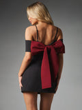 Back view of fitted black mini dress with open back, shoulder straps and oversized burgundy bow