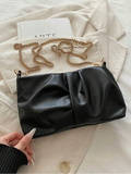 Black ruched faux leather shoulder bag with gold chain strap on cream jacket