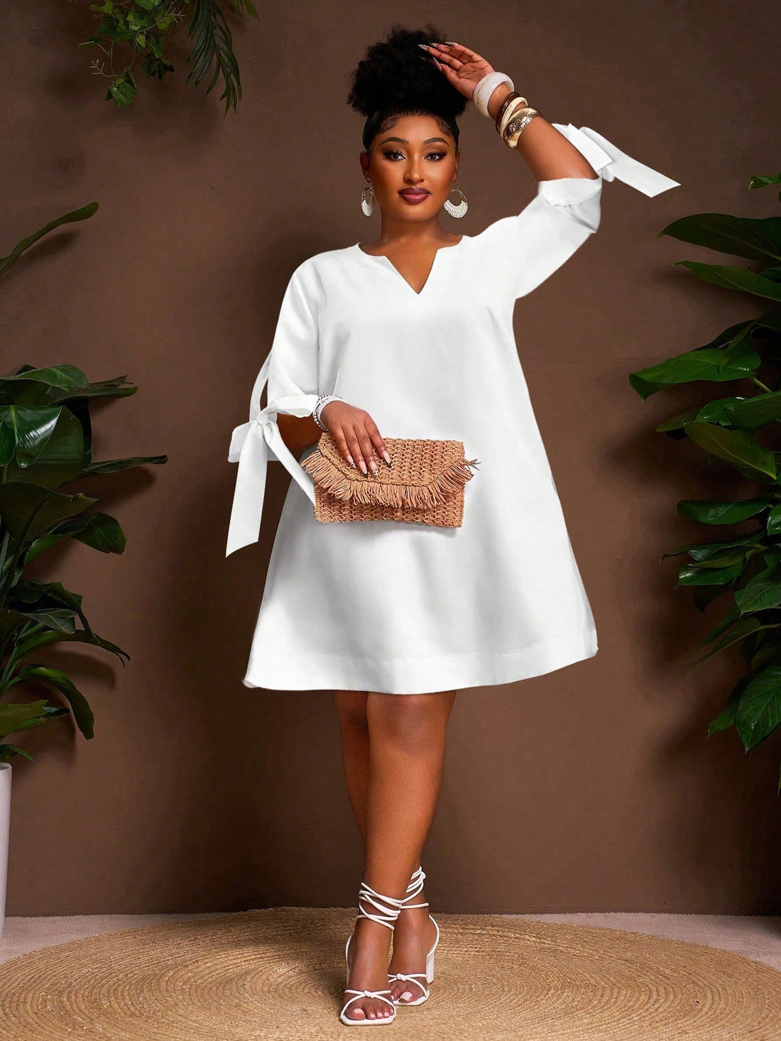 This playful plus size white mini dress features a flattering V-neck and a charming tie front, perfect for sunny summer vacations. Its breezy A-line silhouette keeps you comfortable and effortlessly chic, whether you’re exploring a new city or lounging by the beach. Add a splash of fun to your warm-weather wardrobe with this versatile and stylish summer essential.