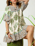 Seated front detail of olive botanical patchwork mini dress with tie neck and puff sleeves