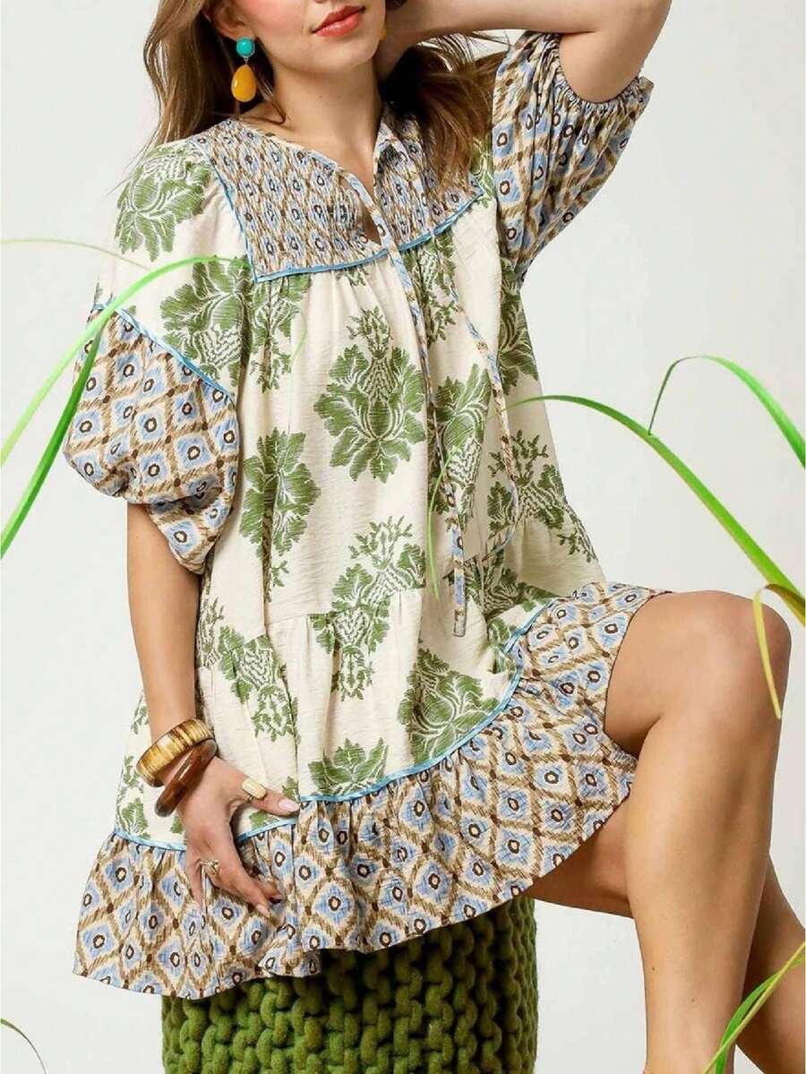 Seated front detail of olive botanical patchwork mini dress with tie neck and puff sleeves