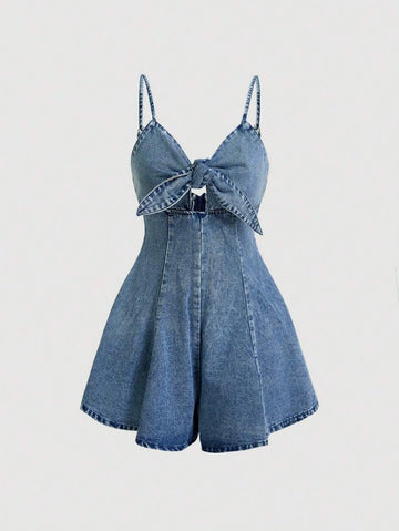 Front view of medium blue washed denim camisole romper with large bow and cutout