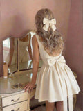 Effortless elegance meets summer style in this chic sleeveless dress. Crafted from luxurious satin, this beige beauty features a flattering regular fit with delicate straps and a stunning backless design accented by a bow detail. The shirred bodice and hidden zipper closure add refined touches, while the short length keeps things fresh and flirty. Perfect for dating, festivals, or casual outings, this versatile piece transitions seamlessly from day to night. 