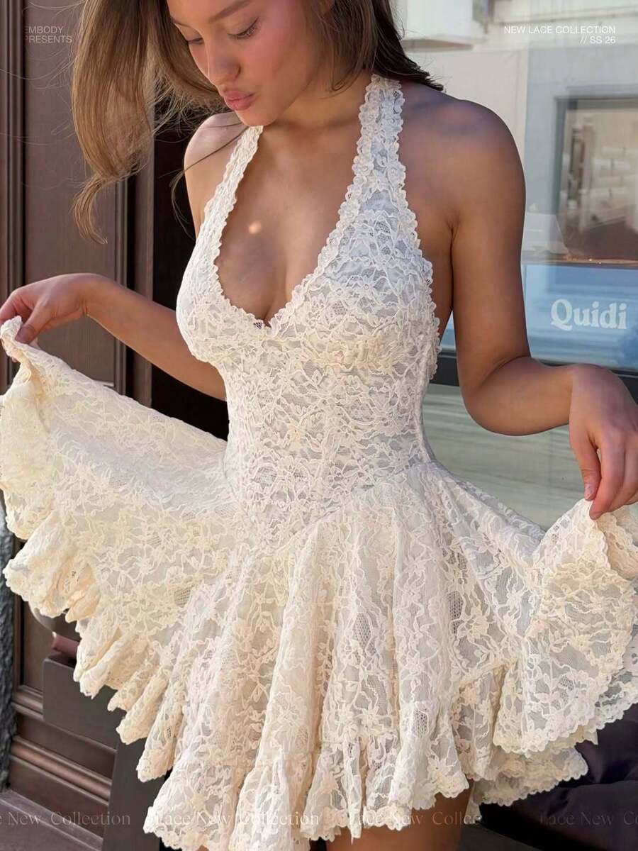 Front close view of a cream floral lace halter mini dress with a plunging neckline and skirt held out to show the ruffled hem
