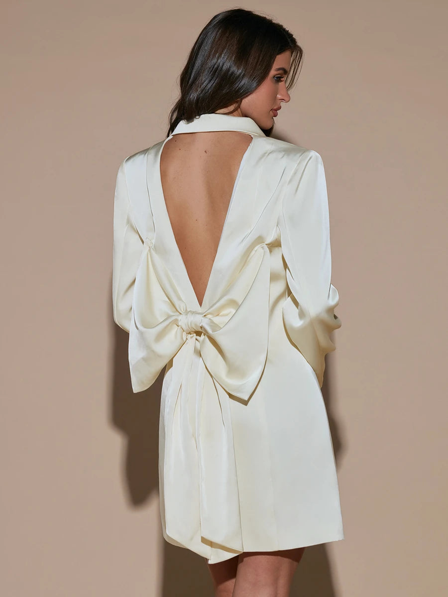 Rear view of ivory satin-look blazer mini dress with open back and large tied bow