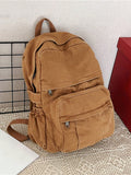 A blue denim canvas backpack with double shoulder straps, displayed against a simple background, with a purple strap visible.