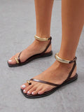 Model wearing chocolate brown flat thong sandals with gold-tone ankle cuffs