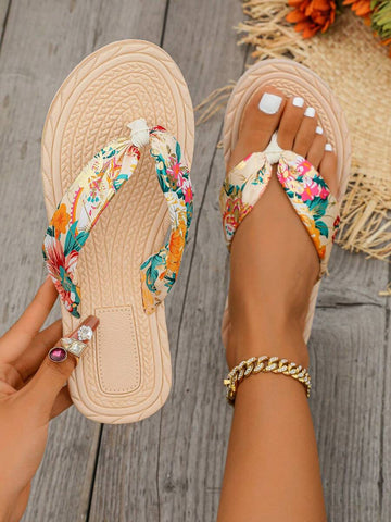 Overhead tropical floral beige flip-flops shown worn and held on a wooden deck