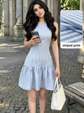 Front view of blue and white striped sleeveless mini dress with drop waist ruffle hem