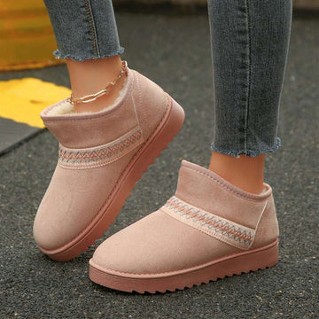 Side view of pink fuzzy ankle boots with embroidered trim and treaded sole