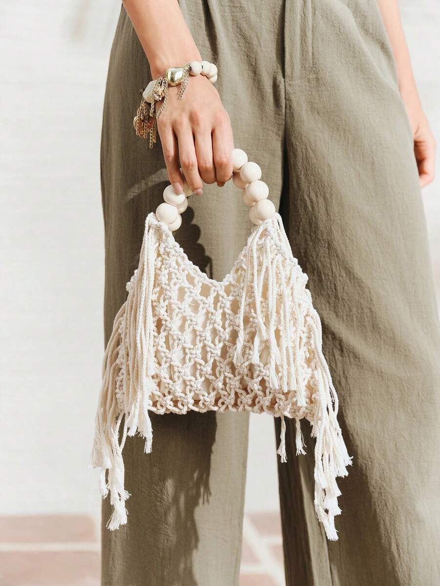 Ivory crochet macrame beach bag with cream bead handle and long side fringe held by model