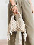 Ivory crochet macrame beach bag with cream bead handle and long side fringe held by model