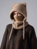 Front portrait of model wearing taupe plush hooded balaclava with ribbed face cover and hanging cords