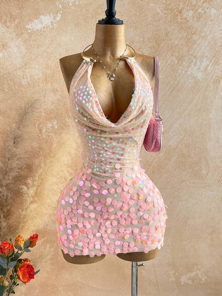 Turn heads in this stunning sequin mini dress designed for unforgettable nights out. Featuring a bold metal draped halter neckline and daring backless design, this bodycon silhouette hugs your curves perfectly while the tie-back detail adds an elegant touch. The shimmering sequin fabric catches the light beautifully, making it ideal for parties and summer getaways. Lined for comfort and crafted from a stretchy polyester-elastane blend, this pink beauty offers both style and wearability. Hand wash to maintai