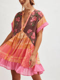 Front three-quarter view of pink floral plaid babydoll mini dress with gathered skirt