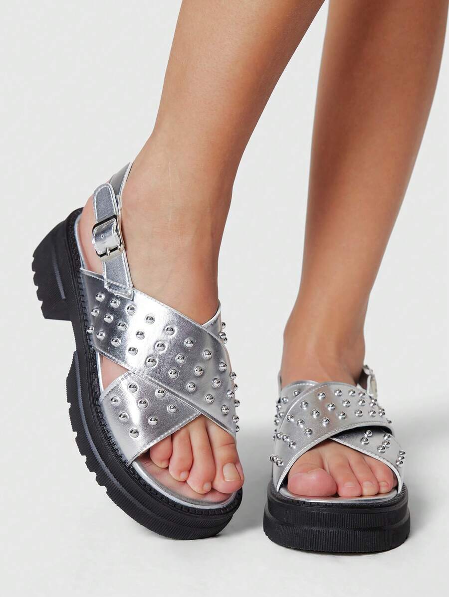Step out with attitude in these Edgy Silver Criss-Cross Roman Sandals. Featuring bold riveted details and a chunky wedge platform, they bring a punk twist to summer style. The criss-cross straps offer a secure fit while adding a dynamic look perfect for turning heads. Comfortable and fierce, these sandals are your go-to for making every step a statement.