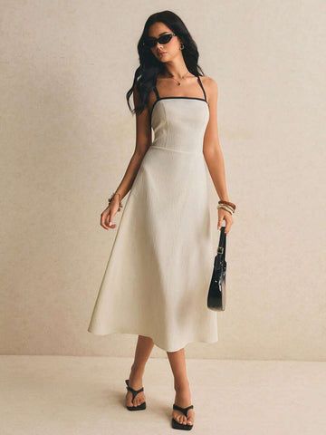 Front full-length view of an apricot midi dress with black spaghetti straps and trim, square neckline, fitted waist, and flared skirt