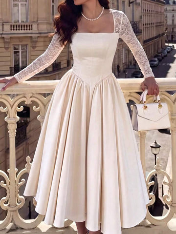 Front view of an ivory square-neck full-skirt dress with sheer floral lace long sleeves and fitted bodice, styled outdoors.