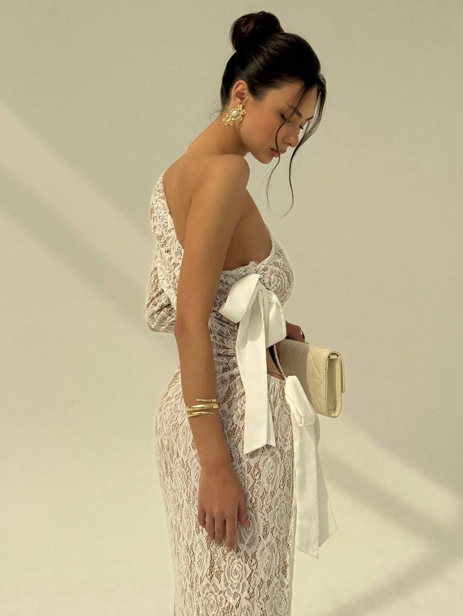 Make a statement in this stunning black lace maxi dress that effortlessly blends sophistication with a touch of whimsy. The asymmetrical silhouette creates an eye-catching flow, while the delicate lace detailing adds timeless elegance. A charming bowknot accent brings playful personality to this show-stopping piece. Perfect for wedding celebrations, prom nights, or any occasion where you want to turn heads and feel absolutely fabulous. Slip into confidence and grace with every step.