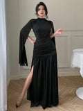 Make a statement at your next formal affair in this stunning black maxi dress. The ruched waist creates a flattering silhouette while dramatic flared sleeves add an unexpected touch of flair and movement. Perfect for galas, weddings, or any occasion calling for sophisticated elegance with a hint of playful drama. The timeless black hue pairs effortlessly with your favorite accessories, letting you shine in understated luxury.